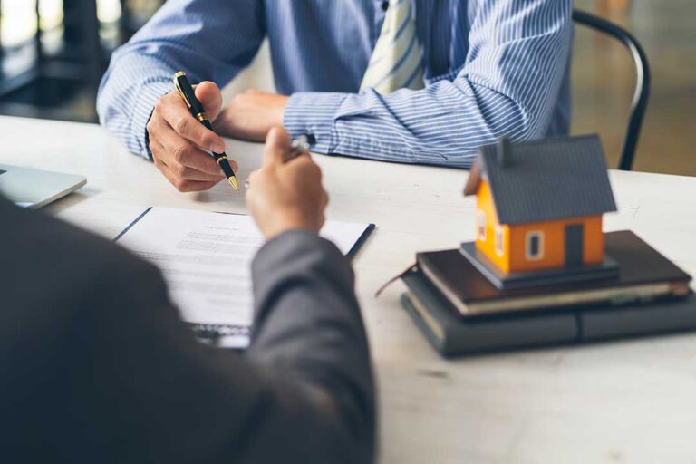 Homeowner reviewing comparable sales and pricing notes at a kitchen table beside property documents.